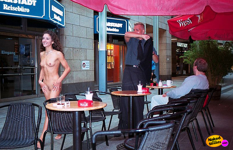 Curly haired girl walks past a terrace with no clothes on
