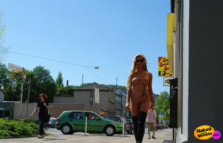 Hot blonde chick with big titties walks along the sidewalk fully nude in public