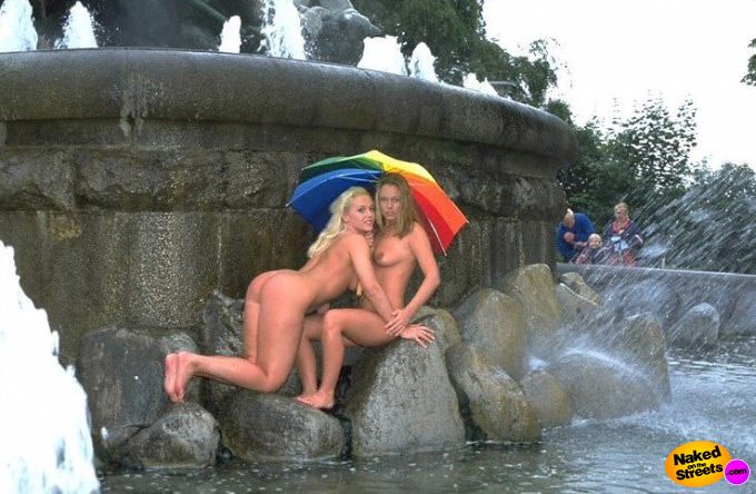 Two nude amateurs posing nude under an umbrellla