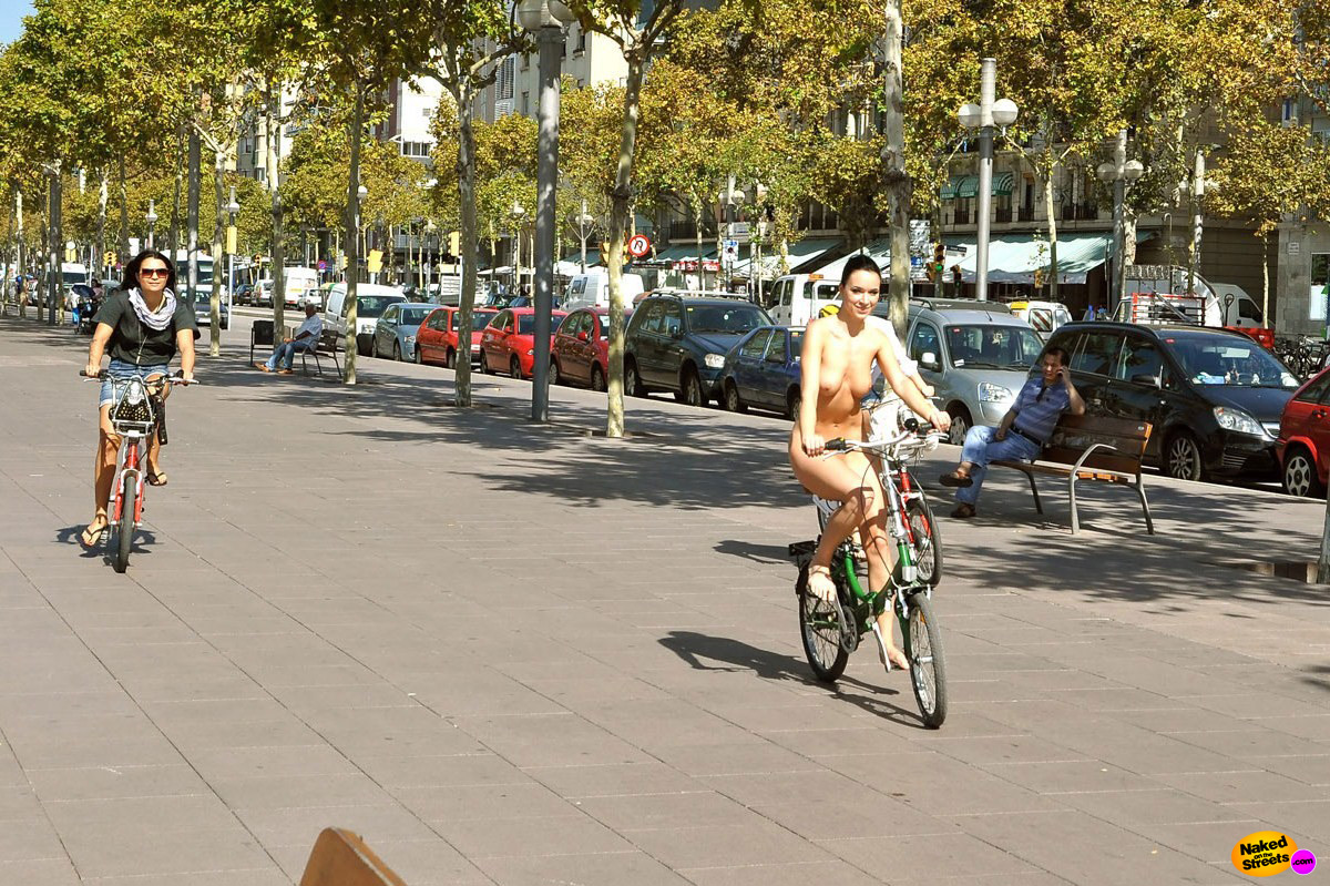 Naughty looking brunette takes a nude city bikeride