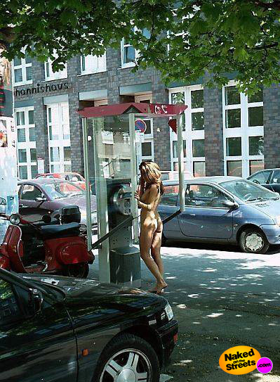 Horny girl stands at a phone booth naked
