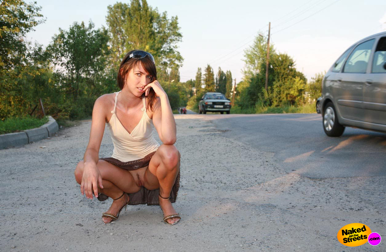 Ridiculously good looking chick showing her pussy by crouching next to road