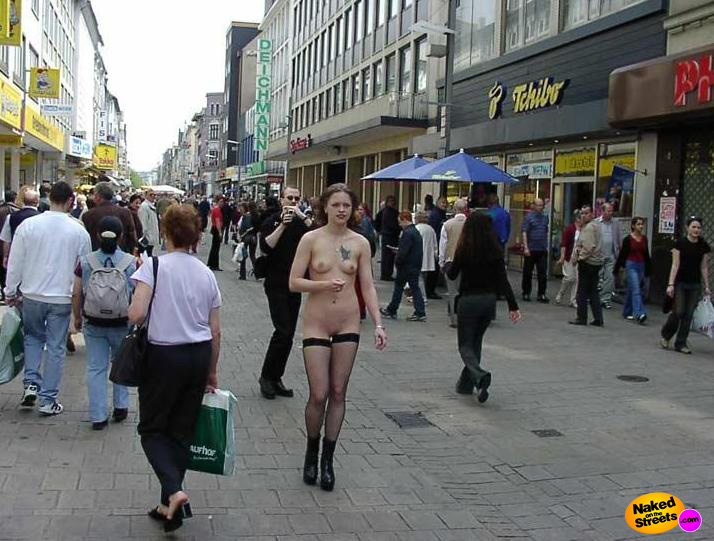 Chick with a tattoo on her sagging tit walking through a busy street nude