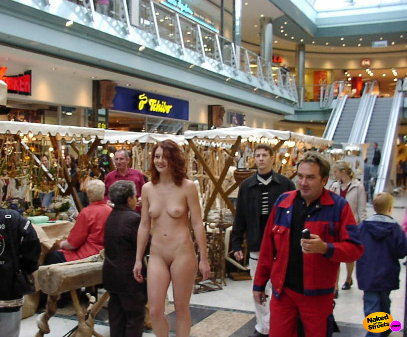 Naughty redhead girl walks around naked in a shopping mall
