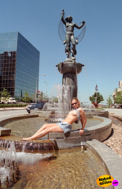 Sexy tourist shows off her tits while posing at a fountain