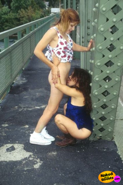 Kinky girl licks her girlfriends pussy on a bridge