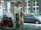 Horny girl stands at a phone booth naked