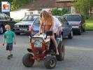 Blonde girl rides a tractor in the nude with a kid watching