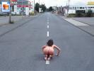 Kinky slut pretends to be a dragrace car by crouching fully nude on a road