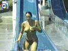 Teen chick goes down a water slide, exposing her big tittie in the process