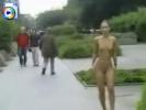 Sexy brunette teen walks along the sidewalk fully nude
