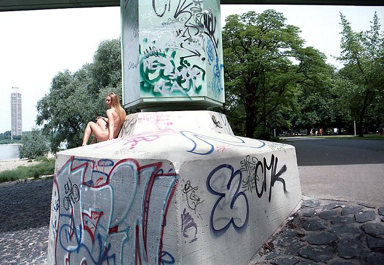Sexy girl posing naked at the base of a big bridge