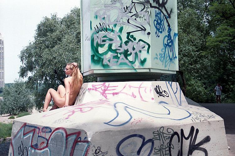 Sexy girl posing naked at the base of a big bridge