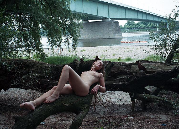 Sexy girl posing naked at the base of a big bridge